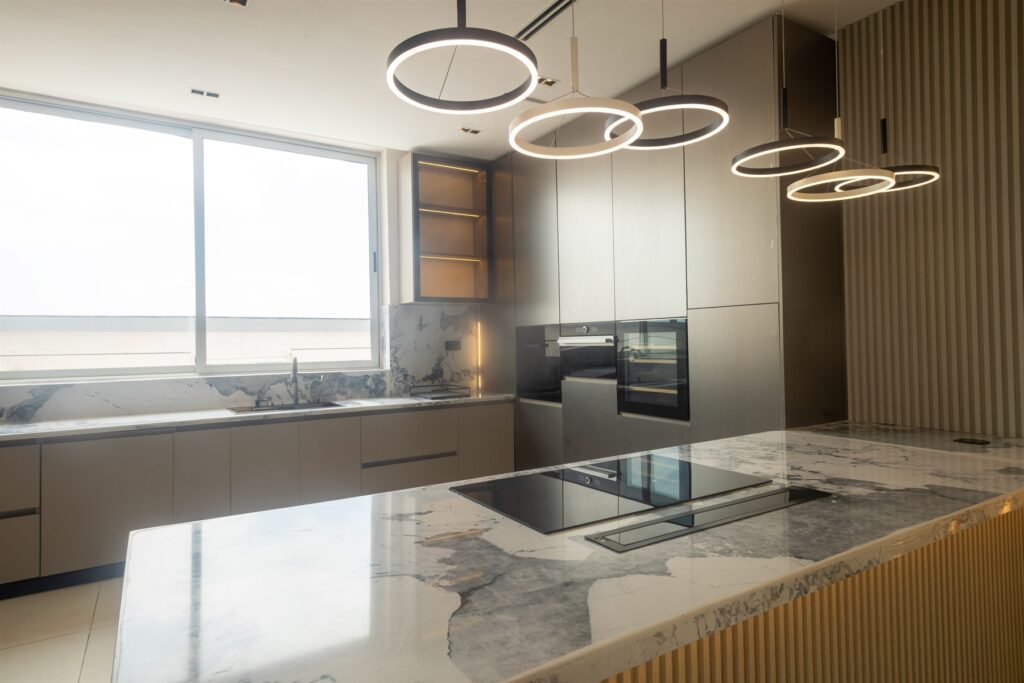 Brum Height 6: Stone-topped kitchen island beneath ring pendant lights